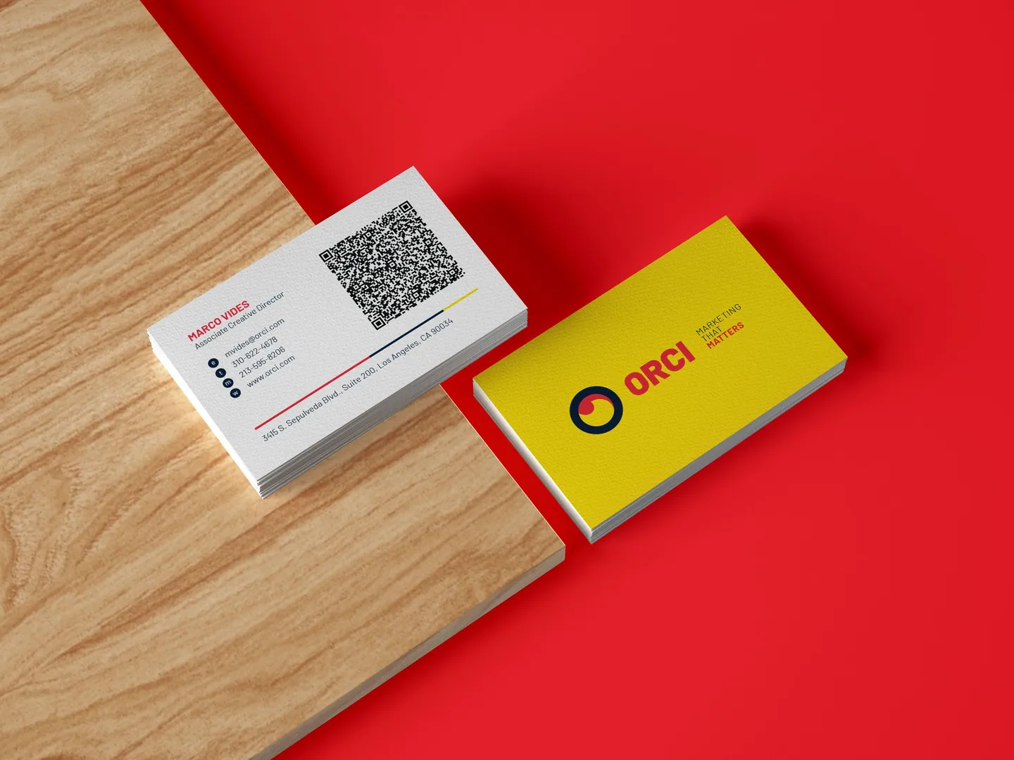 Orci business cards on a wooden surface against a red background.