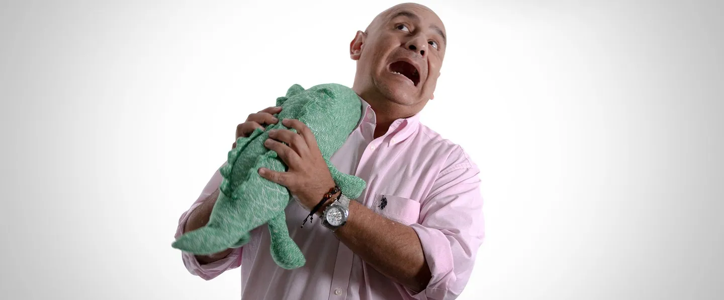 Team portrait: a man hugging a green plush dinosaur.