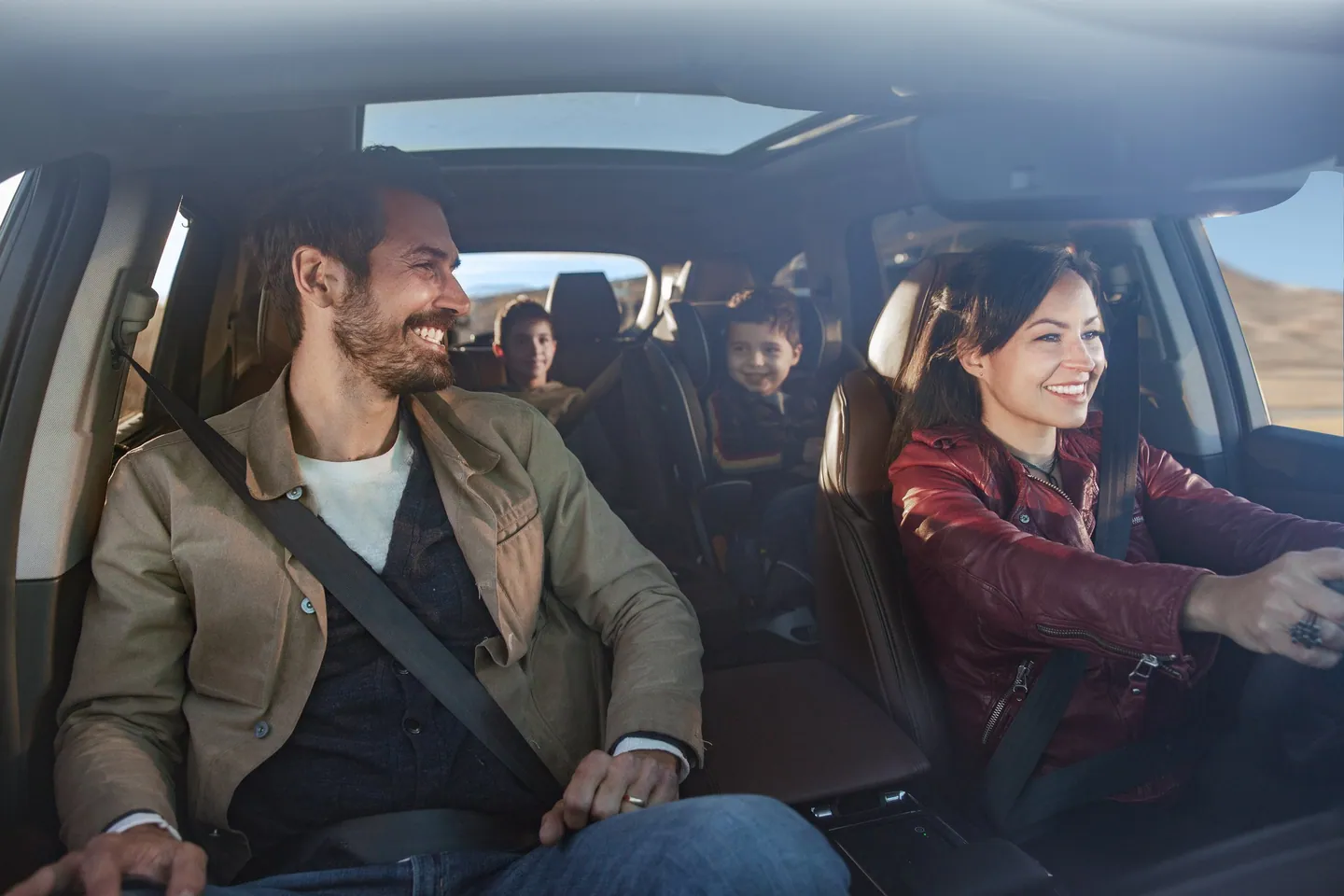A family laughing together inside the Acura MDX on a desert road.